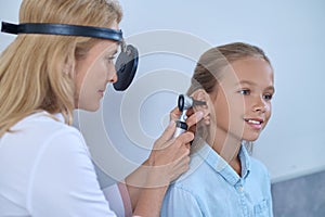 Experienced doctor inserting the auriscope into the patients auditory canal