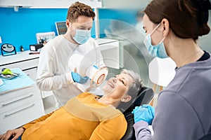 Experienced doctor making x-ray using portable dental tool