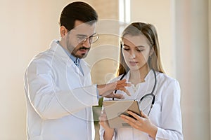 Experienced doctor sharing point of view with colleague using pad