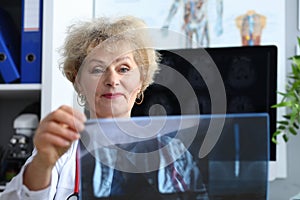 Experienced doctor woman looking at x-ray office