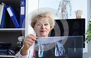 Experienced doctor woman looking at x-ray office