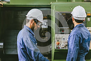 Experienced Engineer Staff Worker working together in metal factory operate setup CNC machine