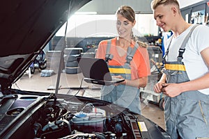 Experienced female auto mechanic checking the engine error codes photo