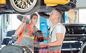 Experienced female auto mechanic with colleague a