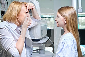 Experienced female ophthalmologist teaching child how to use corrective lenses