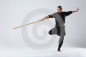An experienced fighter, stands in a fighting posture with a fighting bamboo stick.