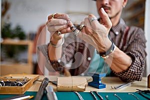 experienced goldsmith tries on rings on his fingers