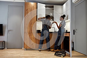 Experienced handyman and demotivated female apprentice repairing kitchen furniture