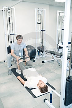 Experienced instructor assisting a man in a rehabilitation workout