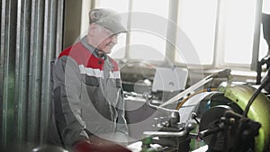 Experienced machinist, factory worker operates a lathe machine in workshop