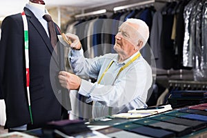 Experienced male tailor brushes a new jacket in workshop