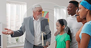 Experienced mature real estate agent shows family around apartment for sale rent points