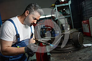 Experienced mechanic in work clothes performing welding work in workshop