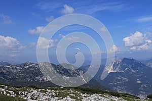 Experienced parachutist flies in the right wind and drives a parachute around the Austrian Alps. Paratrooper with a white-blue