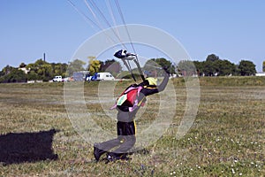 An experienced parachutist landed successfully and pulls the slings with a parachute