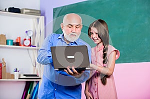 Experienced pedagogue. Teacher help schoolgirl. Little girl with man tutor study hold laptop. Online lesson. Pedagogue