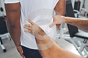 Experienced physical therapist palpating patient lower back