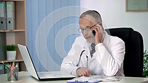 Experienced physician talking on phone, consulting patient about treatment