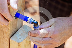 An experienced plumber connects blue PVC pipe to a water piping system