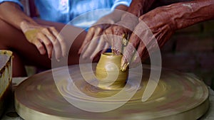 Experienced potter makes clay pot on wheel lady watches