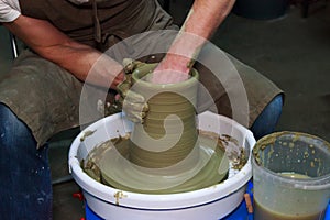 Experienced potter makes a large vase on a potter`s wheel. clay product. hands of a potter. reportage shooting