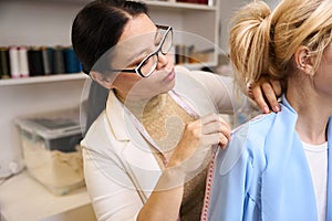 Experienced seamstress using measuring tape during fitting