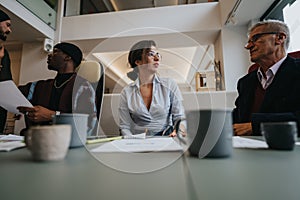 Experienced senior businessman guiding a younger female colleague during a collaborative work session in a modern office