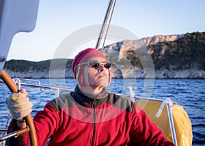 An experienced skipper steers the yacht peering into the distance