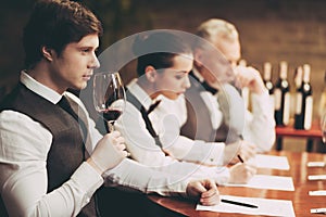 Experienced sommelier explores taste of wine in restaurant. Young waiter tastes alcoholic beverages.