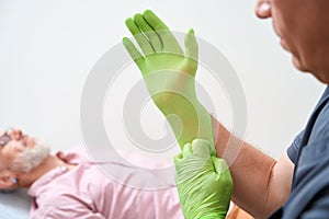 Experienced specialist puts on protective gloves before examining a patient