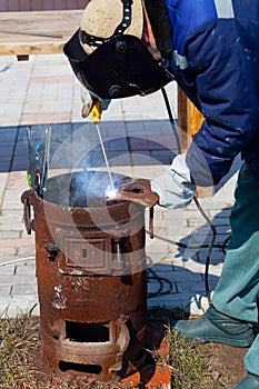 An experienced welder at work. Preparation and welding process of cast iron furnace. Selection focus. Shallow depth of field