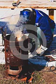 An experienced welder at work. Preparation and welding process of cast iron furnace. Selection focus. Shallow depth of field.