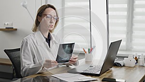 An experienced woman doctor in her office examines an x-ray. Diagnosis of diseases with the help of technology.