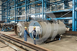 Experienced worker checking the quality of manufactured boilers photo