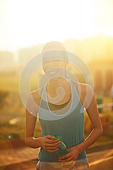 Experiencing a sense of elation and happiness after her run. a young woman drinking water after her run.