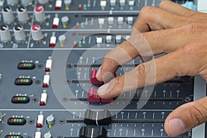 An expert adjusting audio mixing console.select focus