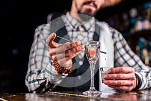 Expert bartender adds ingredients to a cocktail in pub