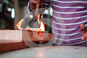 Expert carpenter burning a wood slab with a professional gas burner. Flames and smoke, fire and timber.