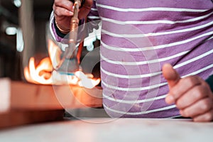 Expert carpenter burning a wood slab with a professional gas burner. Flames and smoke, fire and timber.