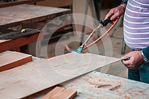 Expert carpenter burning a wood slab with a professional gas burner. Flames and smoke, fire and timber.