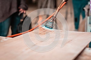 Expert carpenter burning a wood slab with a professional gas burner. Flames and smoke, fire and timber.