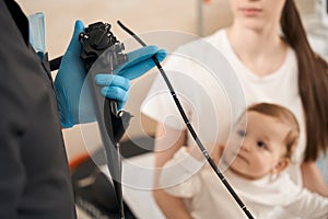 Expert endoscopist preparing infant for endoscopy procedure in mother presence