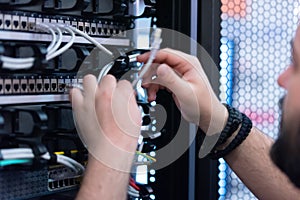 An Expert Engeneer in datacenter server room  connecting cables in server cabinet in network server room photo