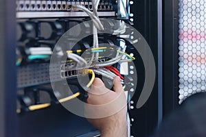 An Expert Engeneer in datacenter server room  connecting cables in server cabinet in network server room