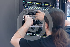 An Expert Engeneer in datacenter server room  connecting cables in server cabinet in network server room