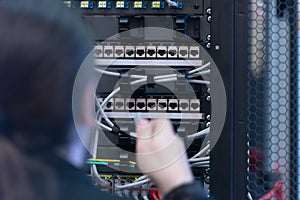 An Expert Engeneer in datacenter server room  connecting cables in server cabinet in network server room