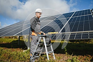 Expert is inspecting quality of a solar batterys. Worker in uniform and helmet with equipment. Ecology power