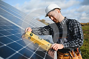 Expert is inspecting quality of a solar batterys. Worker in uniform and helmet with equipment. Ecology power