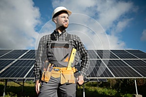 Expert is inspecting quality of a solar batterys. Worker in uniform and helmet with equipment. Ecology power