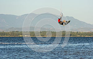 Expert Kitesurfer Jumping a Back Roll with  Sea Watrer Splashes during Golden Hour